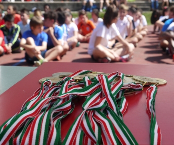 In primo piano le medaglie; in secondo piano li alunni schierati e seduti pronti a cominciare.