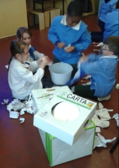 I bambini spezzettano con le mani la carta.